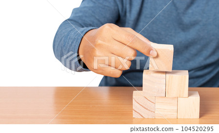 Young man stacking wooden blocks. Young man stacking wooden blocks. 104520295