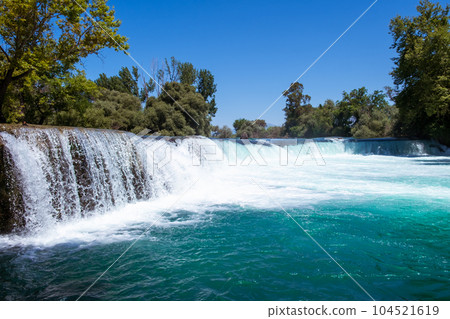 Manavgat waterfall Manavgat River is near the city of Side, 3 km north of Manavgat in Turkey. A wide stream of water falls from a low height. 104521619