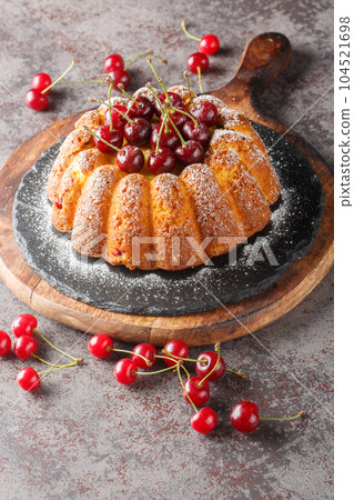 Tasty baked cherry bundt cake close-up on a wooden board. Vertical 104521698