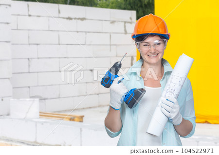 Female builder in a hard hat with a drill in her hands. 104522971