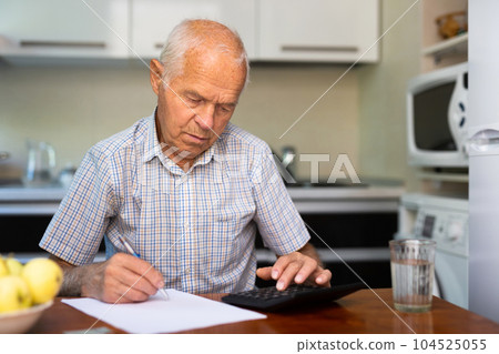 An elderly man is counting money at the table An elderly man is counting money at the table 104525055