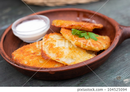 Fried grated potato pancakes with sour cream Fried grated potato pancakes with sour cream 104525094