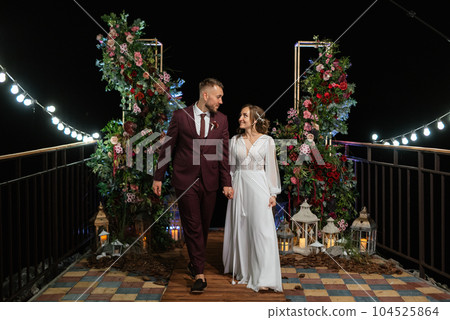 newlyweds in the evening on the wedding arch 104525864