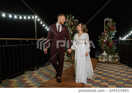 newlyweds in the evening on the wedding arch newlyweds in the evening on the wedding arch 104525865