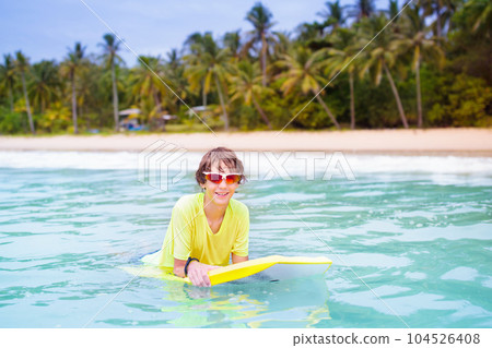 Surfer on tropical beach. Boy surfing. 104526408