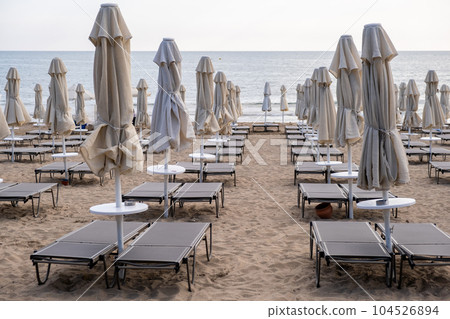 Beach in Antalya, Turkiye. Umbrellas and sun loungers in the assembled state on the beach. Beach in Antalya, Turkiye. Umbrellas and sun loungers in the assembled state on the beach. 104526894