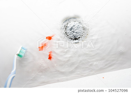 Toothbrush in a white washbasin with blood. Problem with gums. 104527096