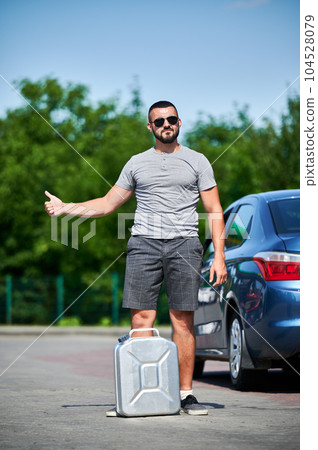 Man trying to catch passing car with gasoline canister in hand. Car runs out of fuel and stalled. Hoping someone drive him to gas station. Man trying to catch passing car with gasoline canister in hand. Car runs out of fuel and stalled. Hoping someone drive him to gas station. 104528079