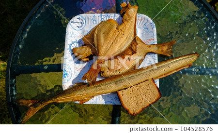 Smoked fish on a paper plate. Delicious home-smoked fish. Two plaice and one wind fish Smoked fish on a paper plate. Delicious home-smoked fish. Two plaice and one wind fish 104528576