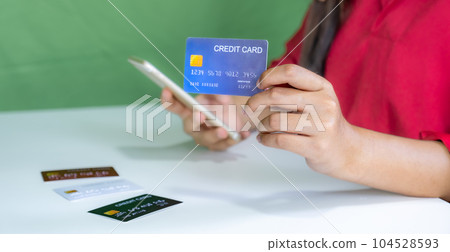 Young consumer woman holding mock up credit card, Ready to spending pay online shopping according to discount products via smartphone and laptop from home Young consumer woman holding mock up credit card, Ready to spending pay online shopping according to discount products via smartphone and laptop from home 104528593
