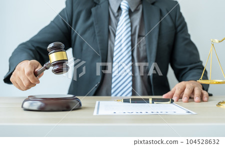Lawyer hand holding gavel hammer hit and providing legal consult business dispute service to the man at the office with justice scale Lawyer hand holding gavel hammer hit and providing legal consult business dispute service to the man at the office with justice scale 104528632