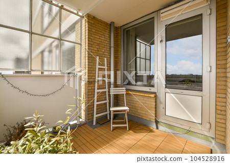 an outside area with a chair and table on the front porch looking out onto the street in the distance is clear blue sky 104528916