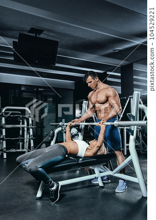 Fitness instructor exercising with his client at the gym. 104529221