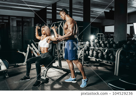Fitness instructor exercising with his client at the gym. 104529236