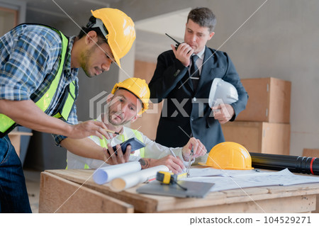 multi ethnic engineer brainstorming and measuring for cost estimating on paperworks and floor plan drawings about design architectural and engineering for houses and buildings. multi ethnic engineer brainstorming and measuring for cost estimating on paperworks and floor plan drawings about design architectural and engineering for houses and buildings. 104529271