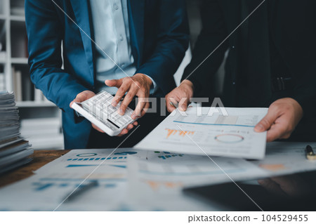 Accountant checking financial statement or counting by calculator income for tax form, Business woman sitting and working with colleague discussing the desk in office. Audit concept. Accountant checking financial statement or counting by calculator income for tax form, Business woman sitting and working with colleague discussing the desk in office. Audit concept. 104529455