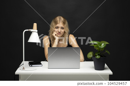 Portrait of a stressed out blonde businesswoman. Frustrated sad woman feeling tired worried about problem sitting in office with laptop. 104529457