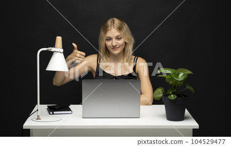 Young happy fun secretary employee business blonde woman showing thumb up while looking in a screen of laptop. Young happy fun secretary employee business blonde woman showing thumb up while looking in a screen of laptop. 104529477