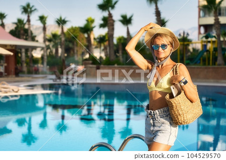 Young happy woman going to work with laptop in summer sunny day near the pool Young happy woman going to work with laptop in summer sunny day near the pool 104529570