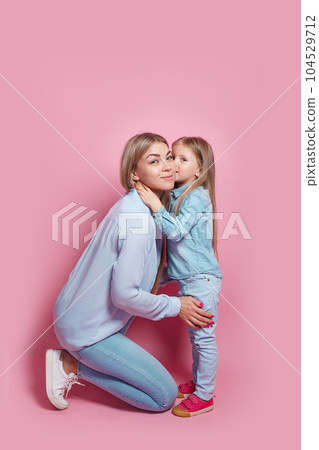 Little daughter hugs and kisses her mom on pink background. Mothers day 104529712