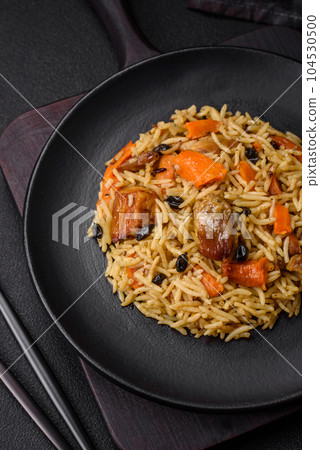 Delicious fresh pilaf with rice, carrots, meat, onions, spices and berries 104530500