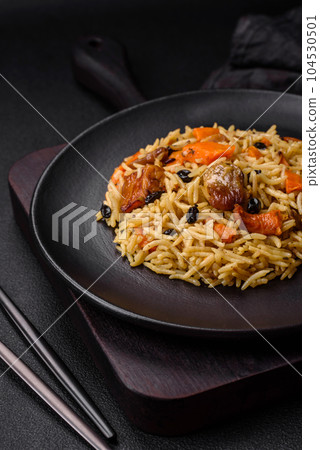 Delicious fresh pilaf with rice, carrots, meat, onions, spices and berries 104530501