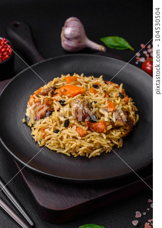 Delicious fresh pilaf with rice, carrots, meat, onions, spices and berries 104530504