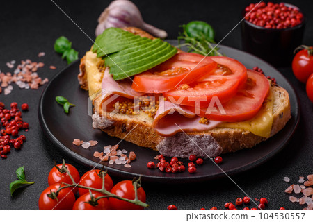 Delicious nutritious grilled toast with ham, cheese, tomatoes and avocado 104530557