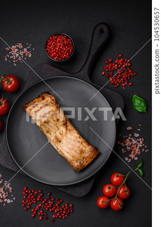 Slice of delicious baked fish with salt, spices and herbs on a ceramic plate Slice of delicious baked fish with salt, spices and herbs on a ceramic plate 104530657
