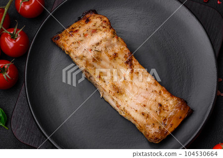 Slice of delicious baked fish with salt, spices and herbs on a ceramic plate Slice of delicious baked fish with salt, spices and herbs on a ceramic plate 104530664