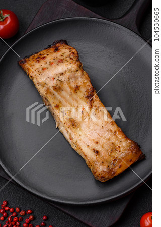 Slice of delicious baked fish with salt, spices and herbs on a ceramic plate 104530665