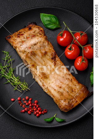 Slice of delicious baked fish with salt, spices and herbs on a ceramic plate Slice of delicious baked fish with salt, spices and herbs on a ceramic plate 104530668