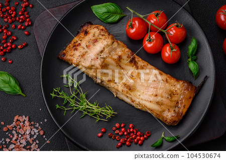 Slice of delicious baked fish with salt, spices and herbs on a ceramic plate 104530674