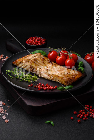 Slice of delicious baked fish with salt, spices and herbs on a ceramic plate 104530678
