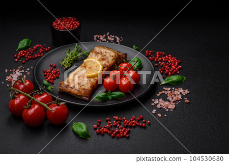 Slice of delicious baked fish with salt, spices and herbs on a ceramic plate 104530680