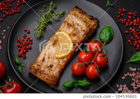 Slice of delicious baked fish with salt, spices and herbs on a ceramic plate Slice of delicious baked fish with salt, spices and herbs on a ceramic plate 104530683