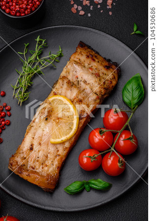 Slice of delicious baked fish with salt, spices and herbs on a ceramic plate Slice of delicious baked fish with salt, spices and herbs on a ceramic plate 104530686