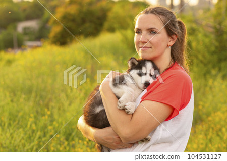 Beautiful young woman is playing with her puppy dog outdoor. 104531127