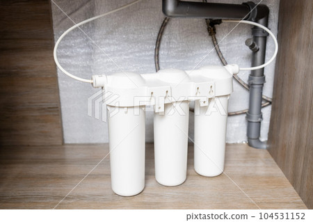 Installation of water purification filters under kitchen sink in cupboard Installation of water purification filters under kitchen sink in cupboard 104531152