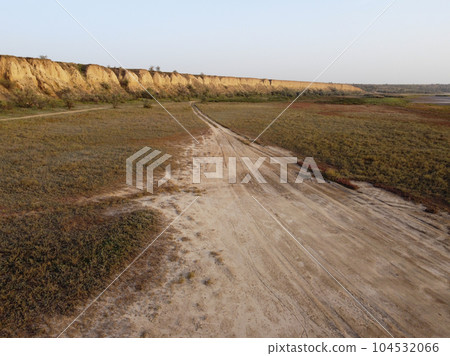 a rural road winding through a landscape of lush green vegetation 104532066