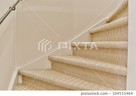 some stairs in a house with white walls and beige carpeted stairs on either side by side to the staircase 104533464