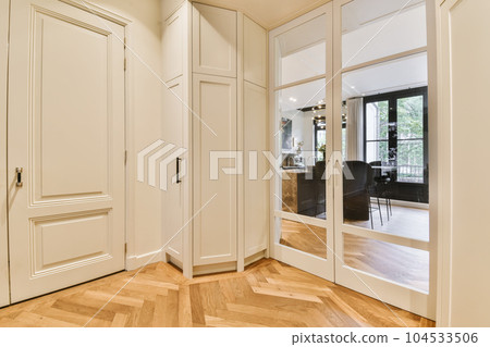 a room with wooden floors and white closets in the middle part of the room there is a large mirror on the wall a room with wooden floors and white closets in the middle part of the room there is a large mirror on the wall 104533506