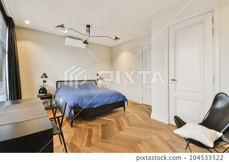 a bedroom with a bed, chair and desk in front of the door that leads to an office space where there is no one 104533522