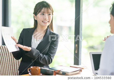 A young business woman serving customers with a document in hand 104533560