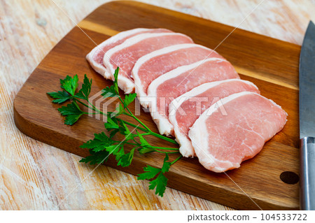 Raw pork tenderloin and greens on wooden table Raw pork tenderloin and greens on wooden table 104533722