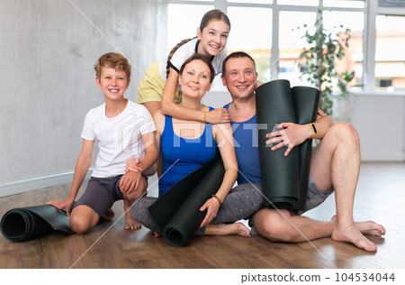 Portrait of happy family engaged in yoga sitting on the floor 104534044