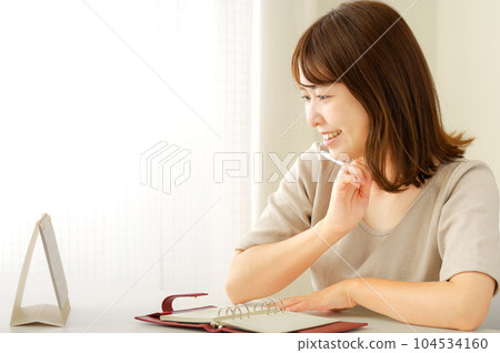 A young woman thinking about her schedule while looking at her notebook 104534160