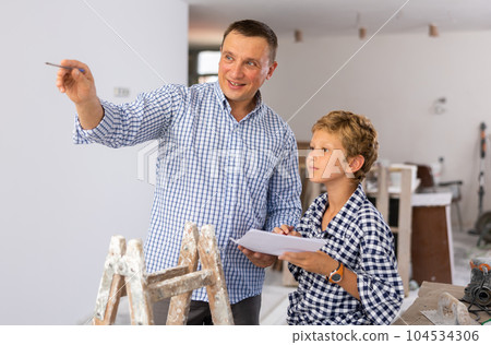 Man showing son blueprints in new home 104534306