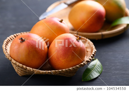Mango fruit (Tommy Atkins) in basket on black background, Tropical fruit 104534550