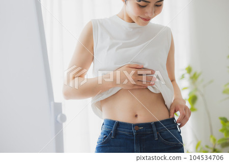 女人在鏡子裡檢查她的肚子 女人在鏡子裡檢查她的肚子 104534706